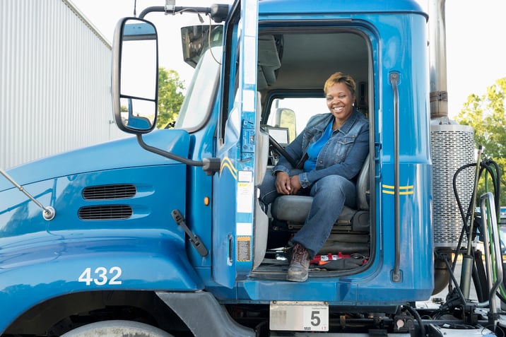 A female truck driver smiling in the front seat - Managing risk