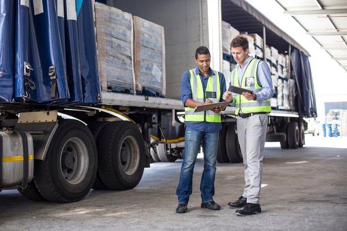 Two truck drivers in high vis vests at work on regulatory updates