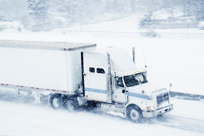 Semi truck drives through snowy conditions