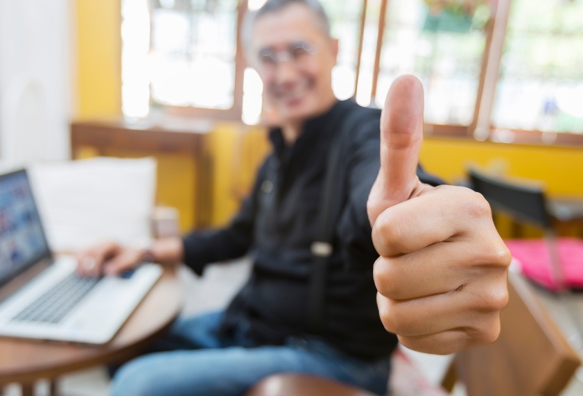 man at to computer giving a thumbs up 