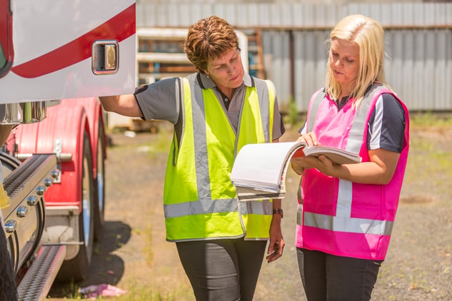 Two women working in trucking wearing high visibility clothing