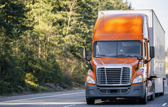 Orange semi drives down the road.