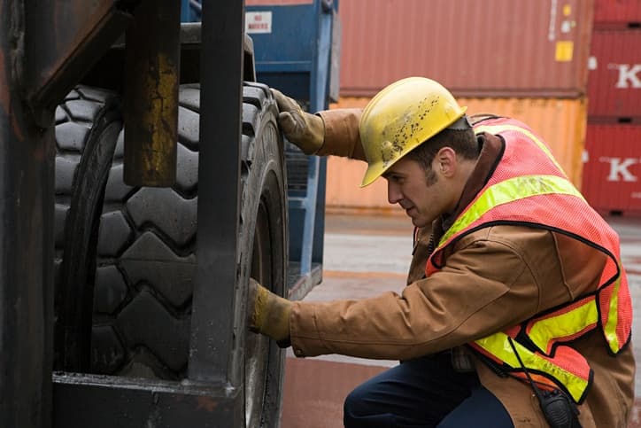 a male safety worker inspecting a semi tire