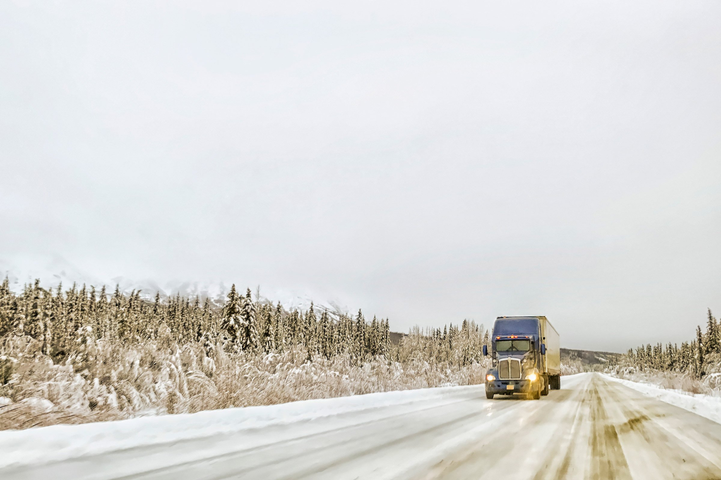 a semi driving down a road in winter