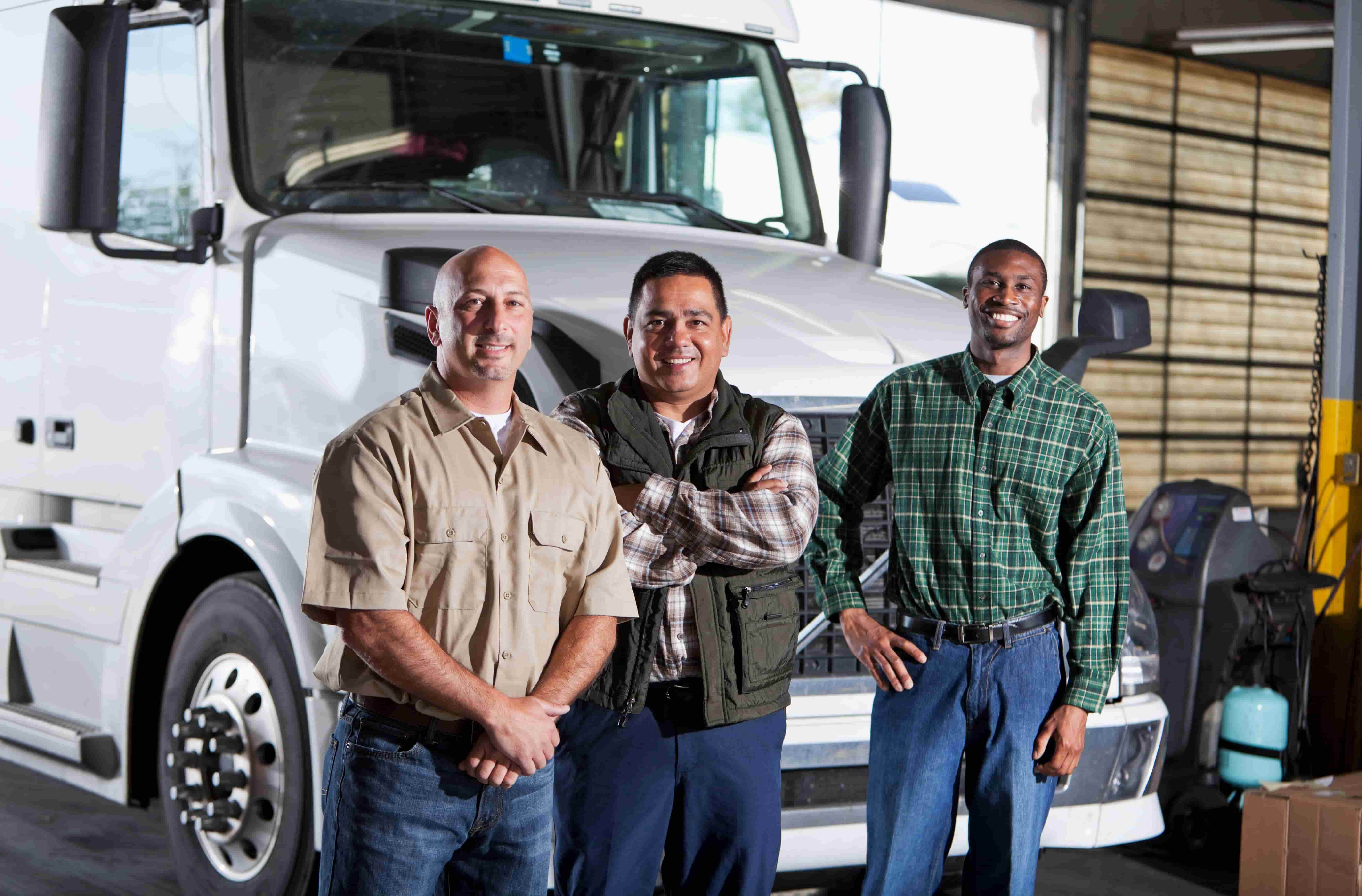 group of motor carrier professionals standing together posing in front of a semi 