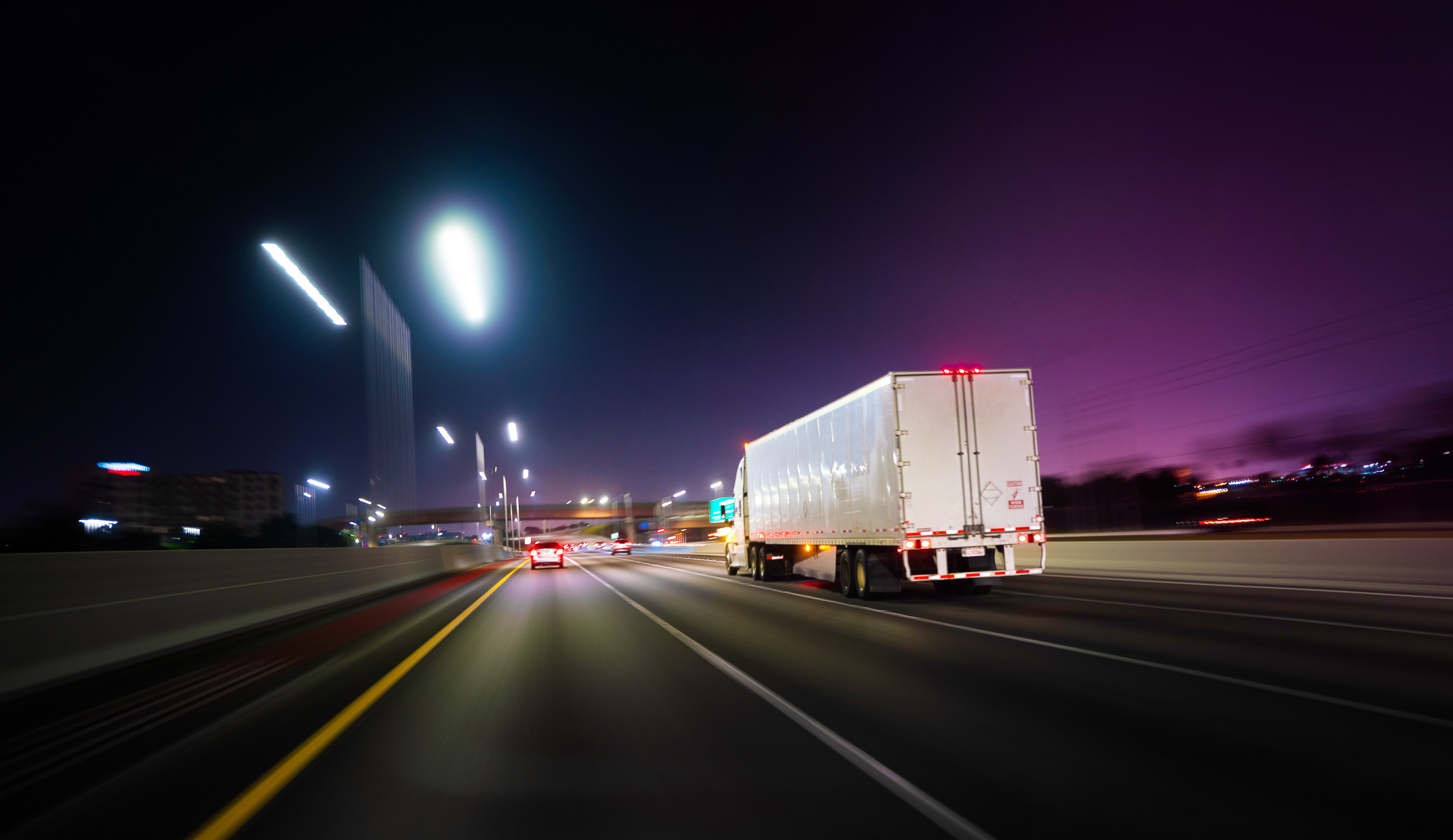 Semi truck drives down the highway at night.