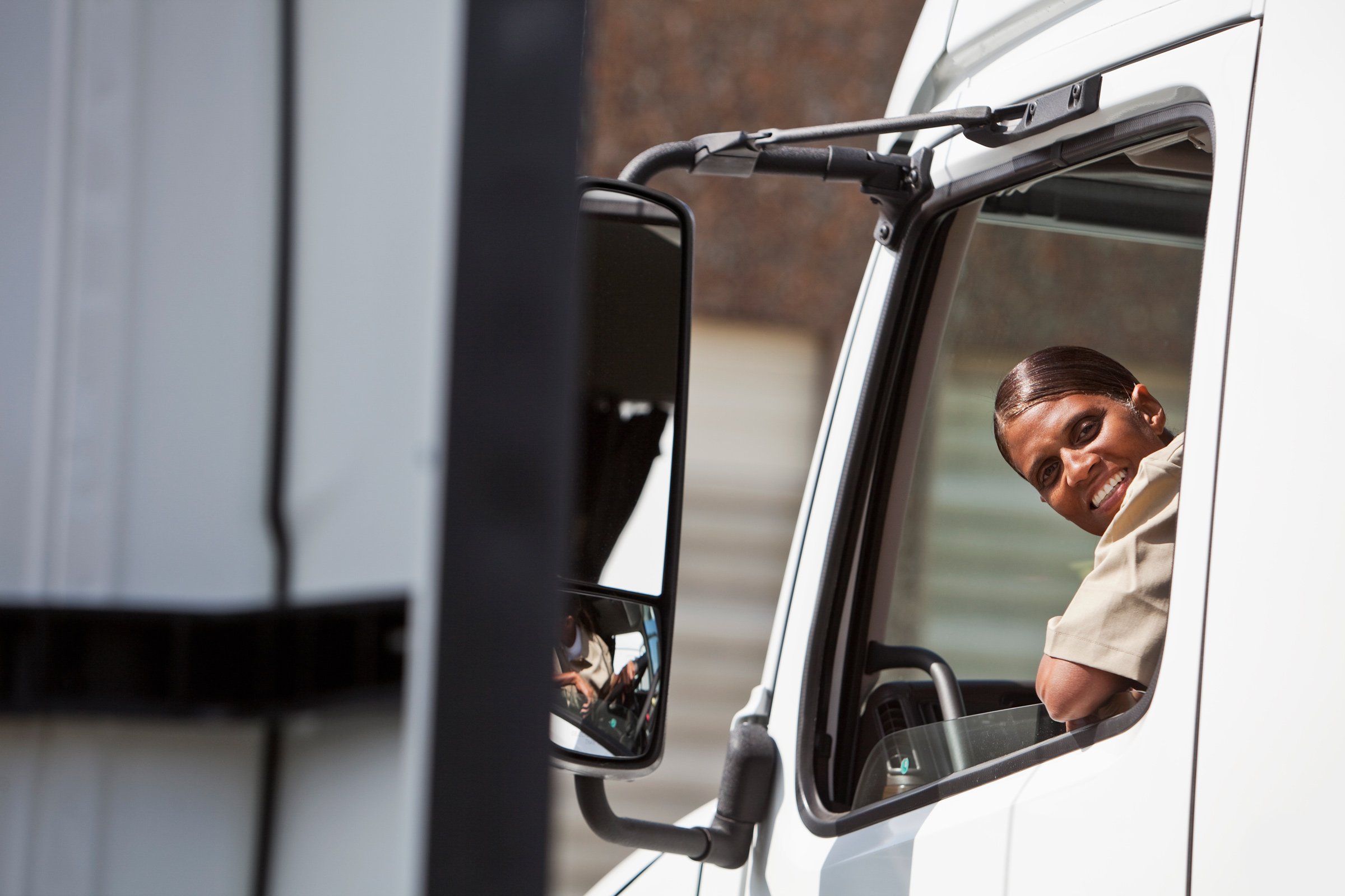 a female truck driver looking behind out the window 