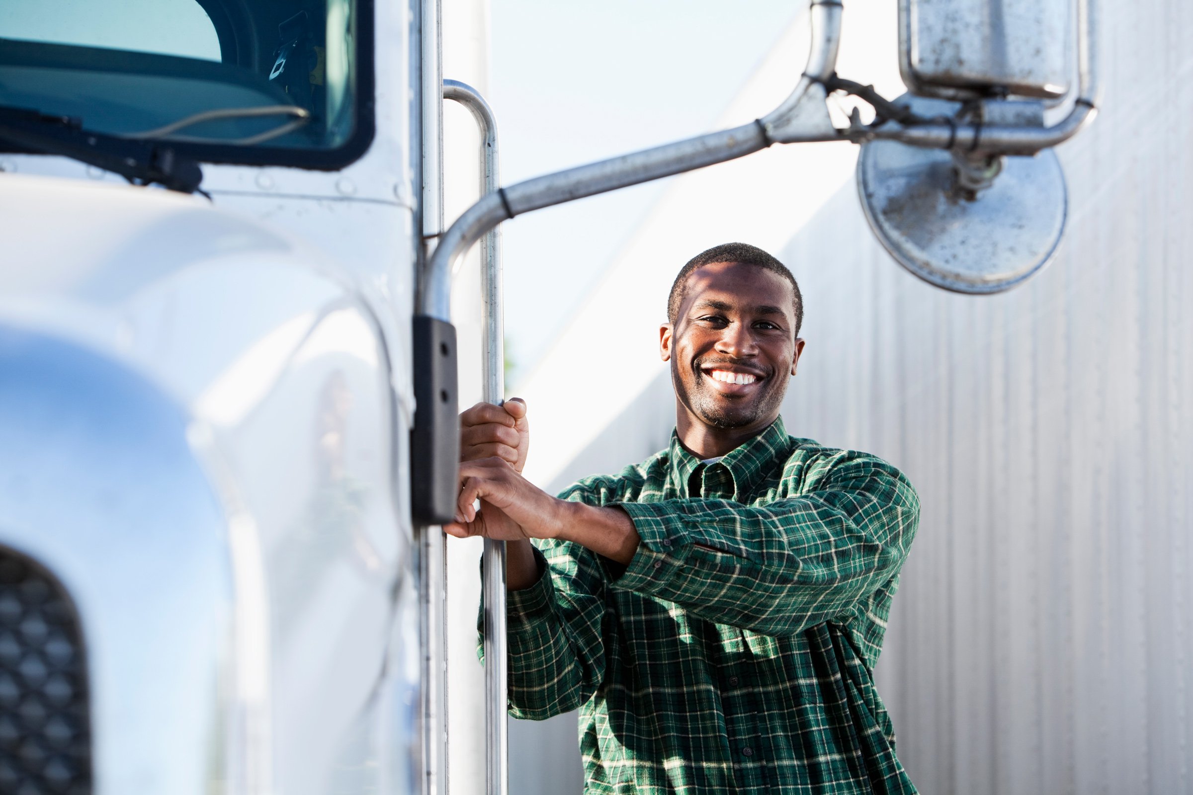 a truck driver smiling and posing next to a semi