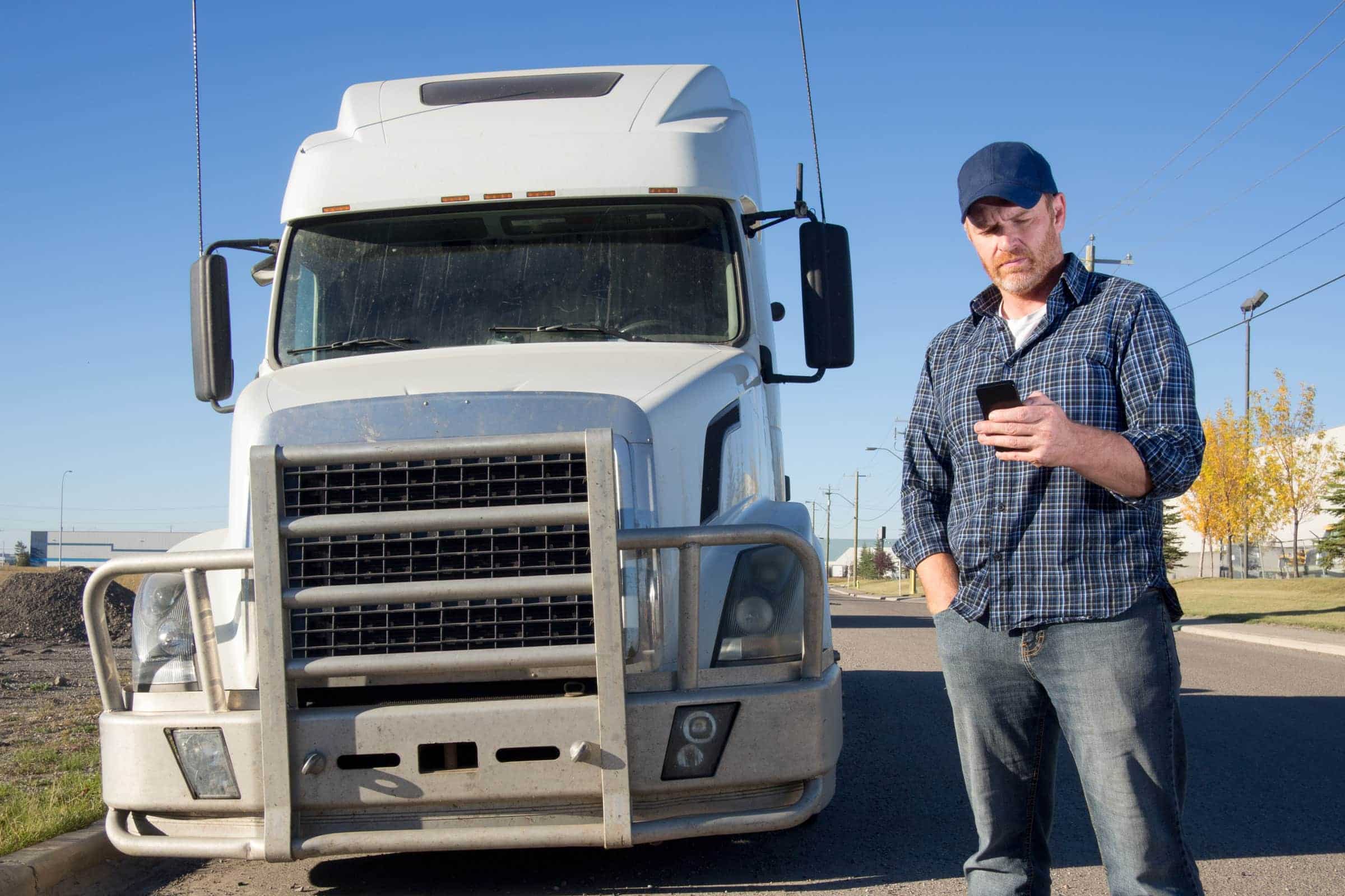 truck driver standing next to a semi on his phone