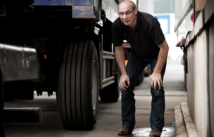 a man knelt down inspecting a tractor trailer