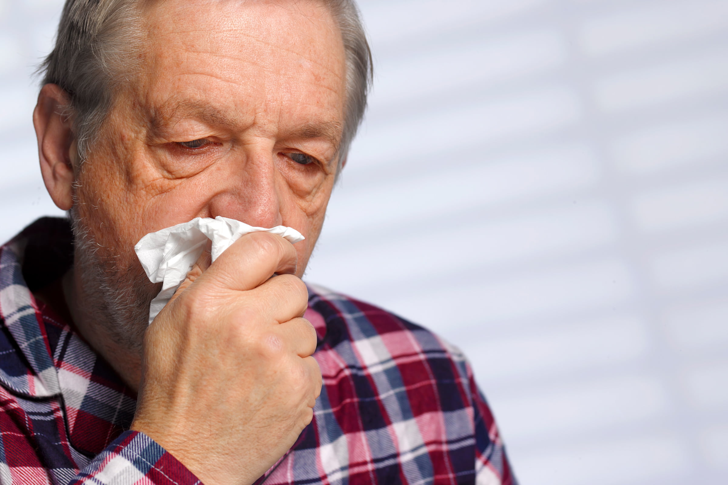 an older man holding a tissue to his mouth