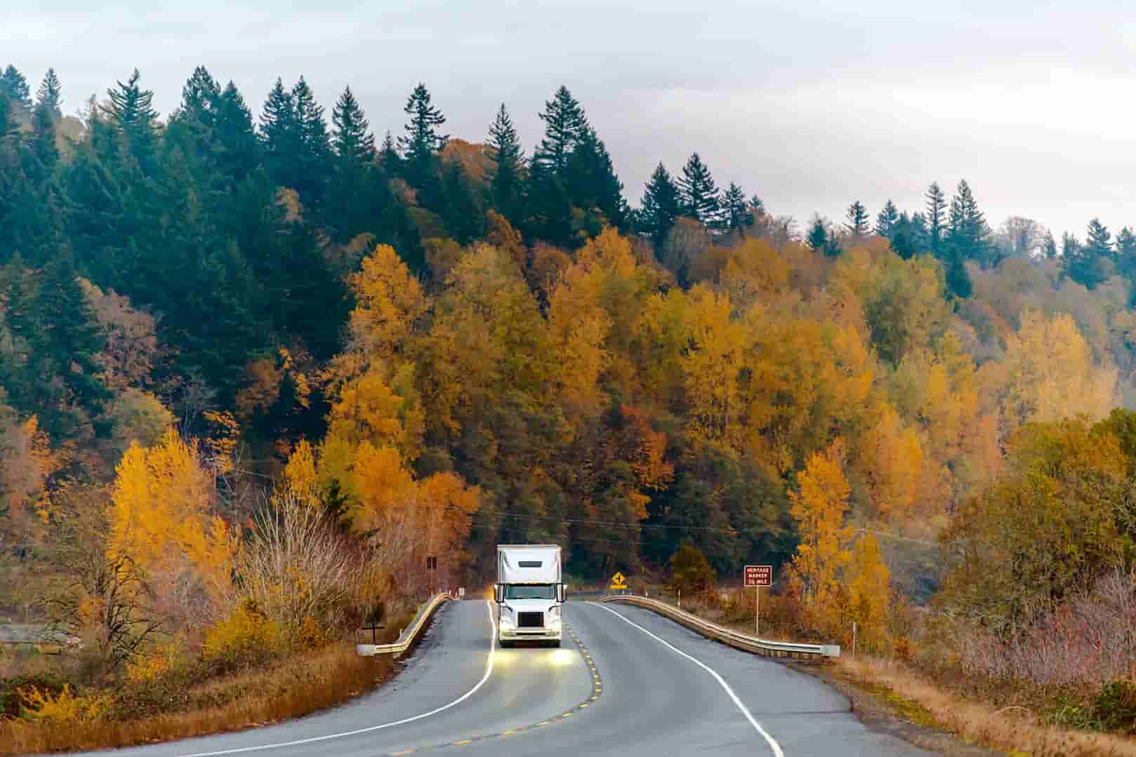 a semi driving through hilly countryside in fall 