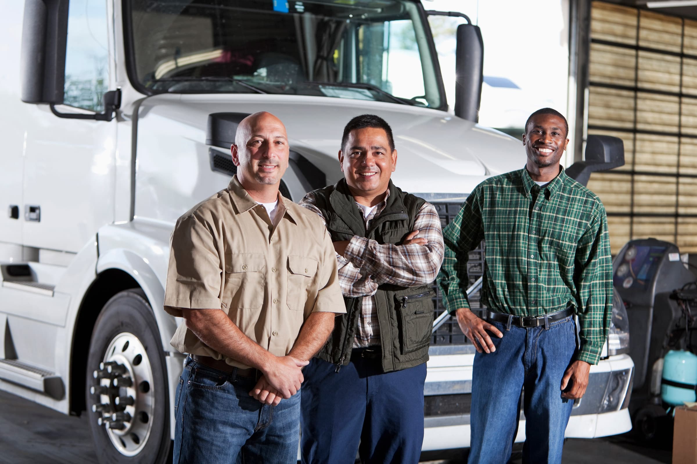 3 motor carriers posing standing in front of a semi 
